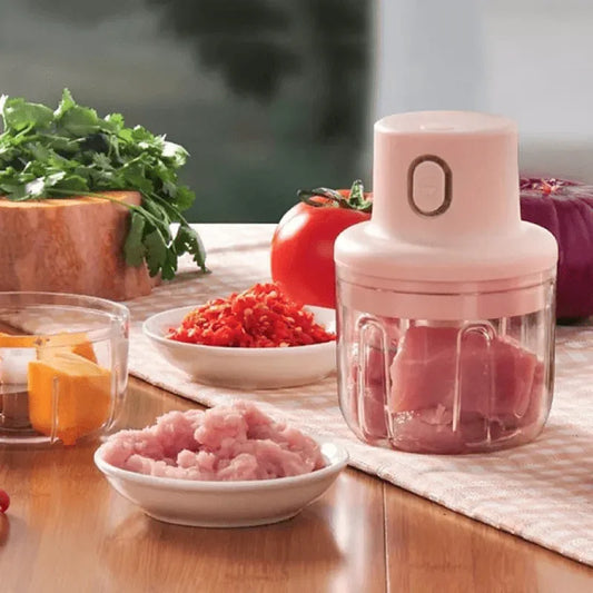 USB rechargeable mini food chopper grinder with chopped meat and vegetables on kitchen table